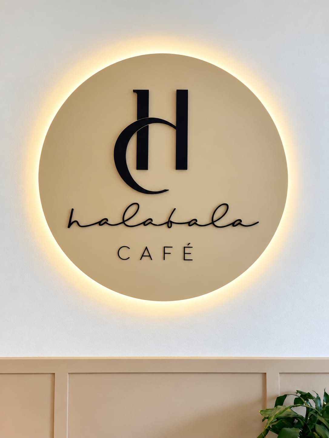 Podsvícené logo Halabala Café propojující iniciály se siluetou Halabalova křesla